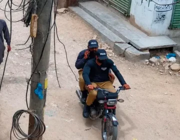 A CCTV camera capturing a street crime scene with a motorbike in a Karachi neighborhood.