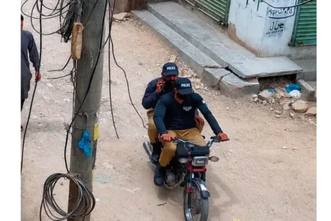 A CCTV camera capturing a street crime scene with a motorbike in a Karachi neighborhood.