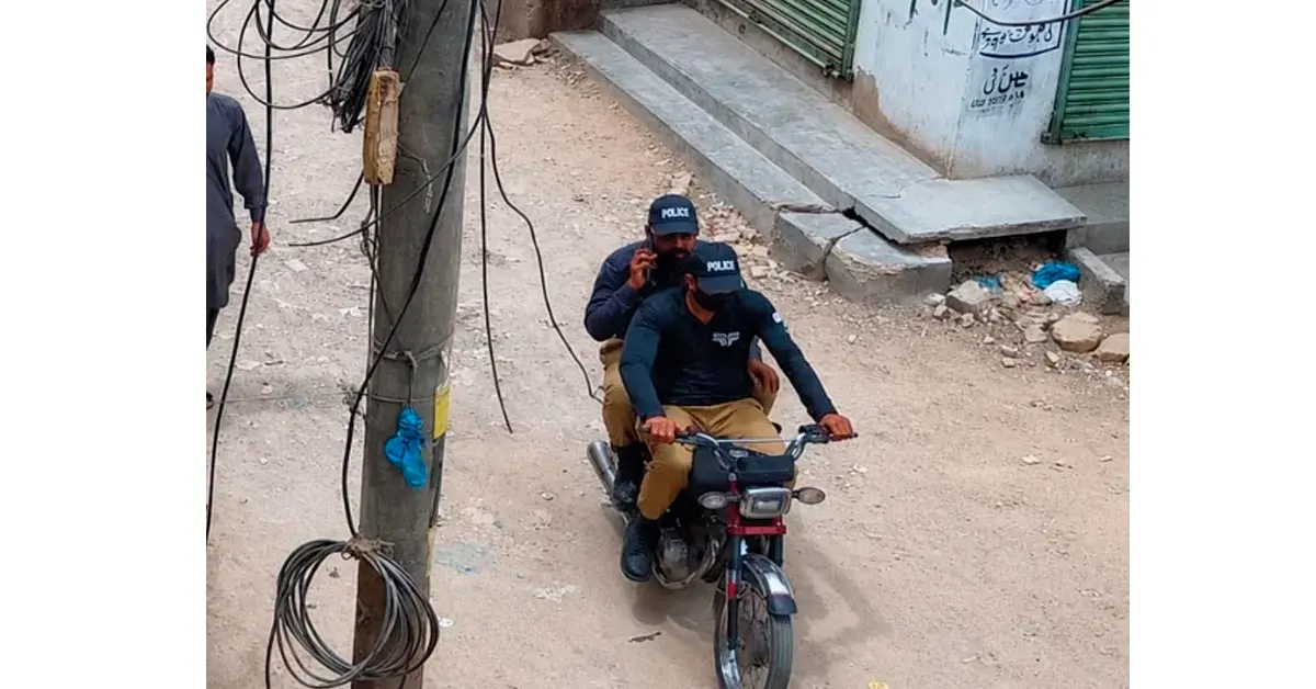 A CCTV camera capturing a street crime scene with a motorbike in a Karachi neighborhood.