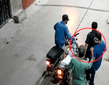 A CCTV frame showing a armed robber looting a citizen at gunpoint outside a house in Karachi.