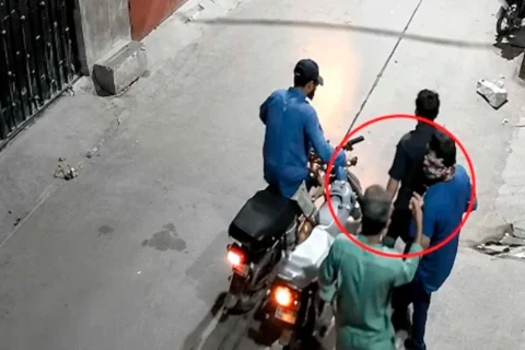 A CCTV frame showing a armed robber looting a citizen at gunpoint outside a house in Karachi.