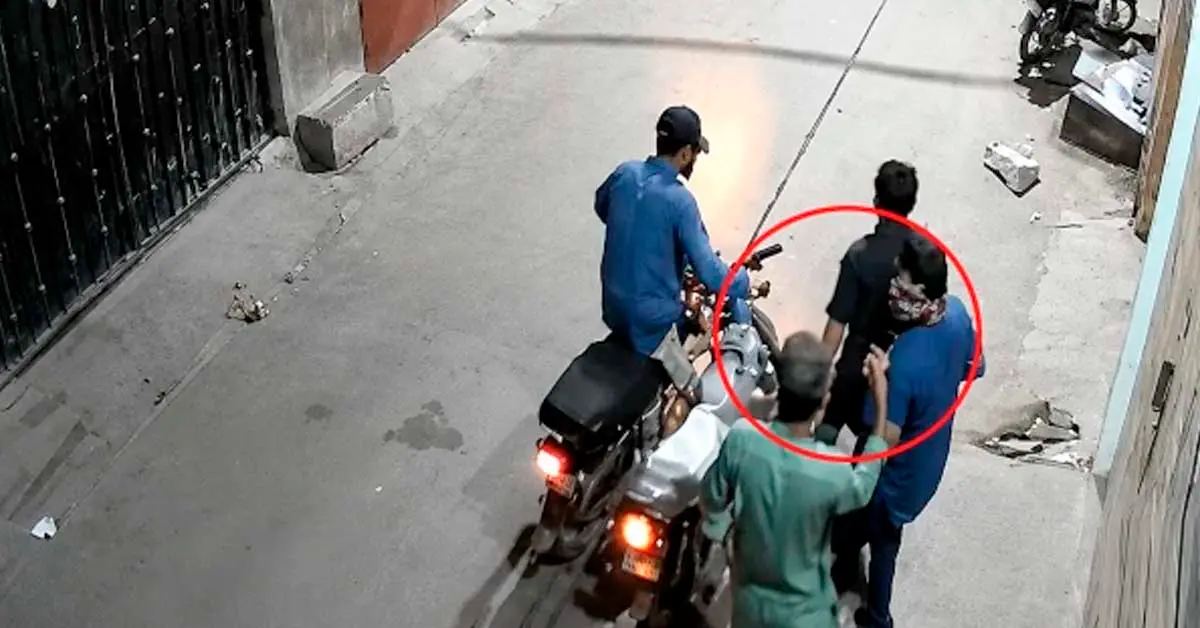 A CCTV frame showing a armed robber looting a citizen at gunpoint outside a house in Karachi.
