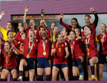 Spanish football players lifting the gold FIFA World Cup trophy in celebration on stage