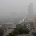 Dark clouds and heavy rain pouring down on Karachi roads and city view